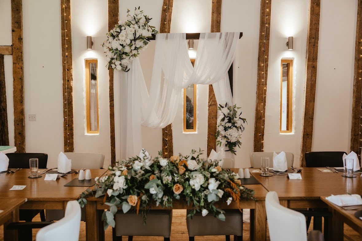 The Crooked Barn top table dressed with florals beneath the oak beams