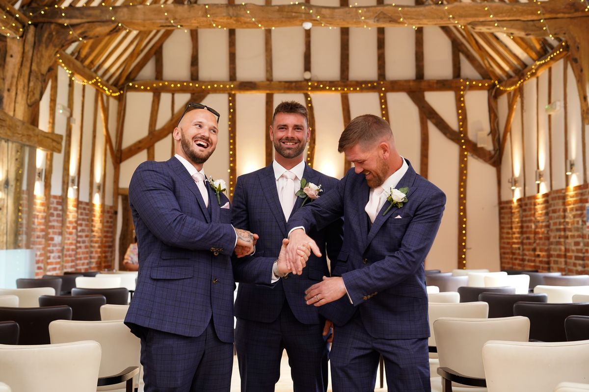 Groomsmen sharing a laugh in the barn