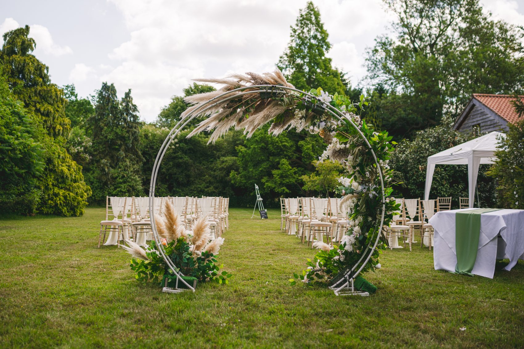 An outdoor ceremony set up with a floral arch on the Ivy Hall lawn